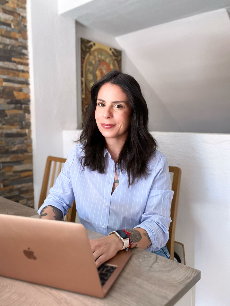 La entrenadora posa mientras usa su Mac.